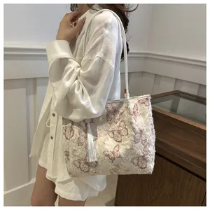 Detail of plush butterfly embroidery and white tassel on large tote shoulder bag
