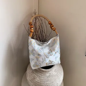 Schicke cremeweiße Stofftasche mit Schmetterlingsstickerei und Bambus-Perlengriffen
