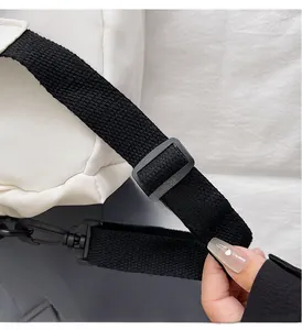 Detailed macro view of high-quality adjustable black strap and metal hook on white bag