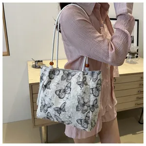 Close-up of tote bag with black butterfly print and elegant beaded handle detail