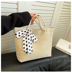 Détail du sac cabas en paille avec broderie de marguerites et ruban à pois au manche