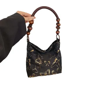 Elegante schwarze Tragetasche mit goldener Schmetterlingsstickerei und Perlen-Tragegriffen