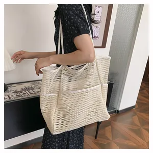 Detalle del bolso tote de malla blanco crema con diseño calado y bolsillo frontal