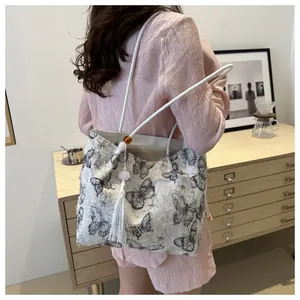 Detail of white canvas tote bag with butterfly print and elegant long tassel charm