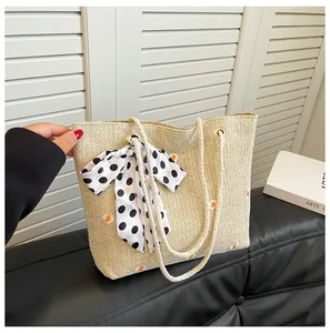 Détail du sac en paille brodé de marguerites, nœud à pois et anses en corde blanche