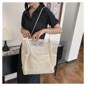 Detalle de un bolso tote beige de malla tejida que muestra los patrones y bolsillos externos