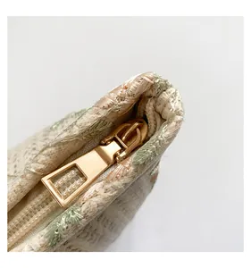 Detail of high-quality gold metal zipper on cream embroidered woven handbag