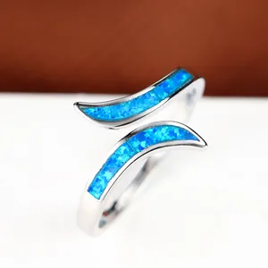 Macro detail of silver-tone open ring featuring blue opal inlay and double-curve design