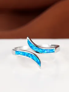 Macro detail of silver open ring featuring vibrant blue opal stones in a modern setting