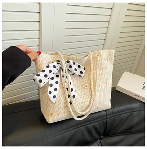 Gros plan d'un sac cabas en paille avec broderie marguerite et foulard à pois chic