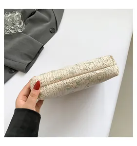 Detail view of woven clutch with delicate floral embroidery and natural texture