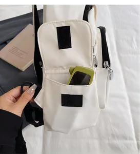 Detail of white canvas bag side pocket with velcro closure and black zipper detail