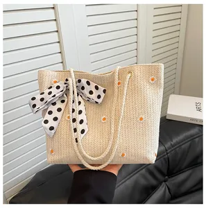 Détail de la broderie marguerite et du foulard en soie sur un cabas en paille