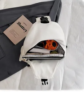 Detail view of the spacious white chest bag interior holding a tablet, umbrella and books