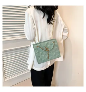 Detail van mintgroene gewatteerde tas met gouden ketting en franje hanger op model
