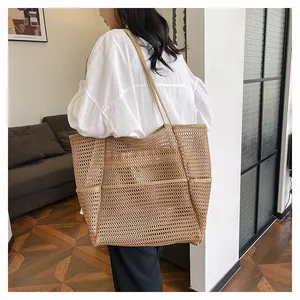 Detalle de un bolso tote grande de malla caqui con correas mostrado en un ambiente interior