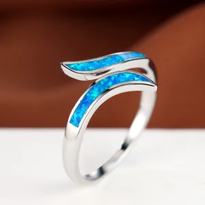 Adjustable silver tone ring with vibrant blue opal inlay set on a stylish wave band