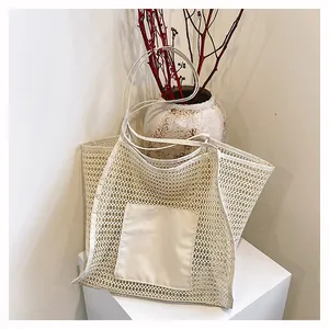 Detalle de bolsa tote de malla crema con bolsillo cuadrado sólido y correas largas al hombro