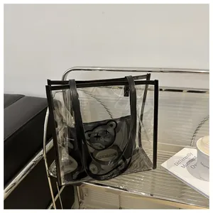 Detail of transparent PVC jelly tote bag with black handles and cartoon bear inner pouch