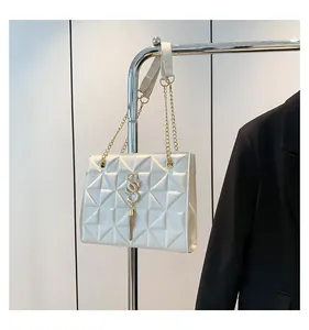 Detail van beige tas met piramide-quiltpatroon, gouden kwastje en ketting schouderriem
