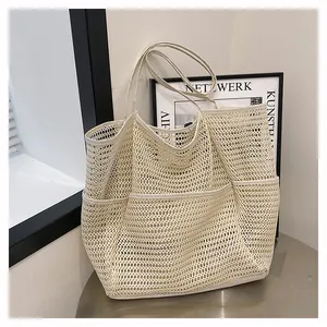 Detalle de un bolso de playa de malla beige con bolsillos exteriores y correas tejidas