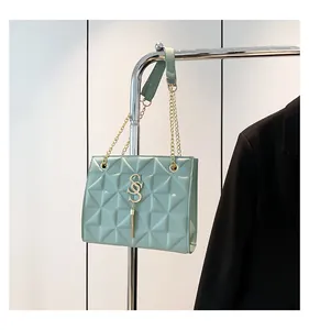 Detail van mintgroene gewatteerde tas met gouden SS-logo en metalen kettingriem