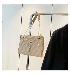Detail van beige gewatteerde tas met gouden logo kwastje en ketting schouderriem