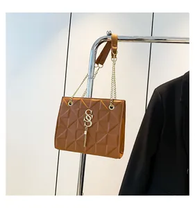 Detail van de bruine handtas met geometrische textuur, gouden ketting en SSS-logo