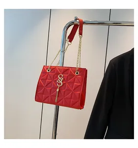 Detail van rode gewatteerde tas met gouden SS-logo en elegante metalen ketting