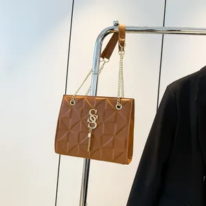 Bruine gewatteerde crossbodytas met gouden ketting en kwastje hangend aan rek
