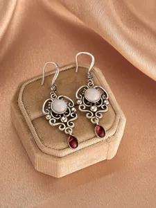 Detailed view of vintage silver earrings with hollow patterns and colorful gemstones