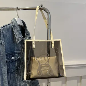 Transparent PVC tote bag with bear print and inner pouch hanging on a metal rack
