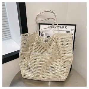 Cream mesh tote bag with three front pockets and long shoulder straps for summer beach use