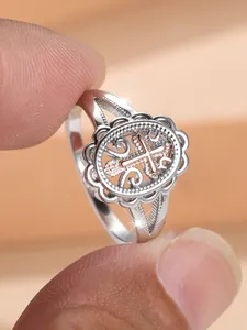 Close-up of vintage hollow lace ring with rose gold cross and silver metal finish