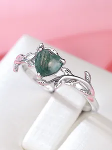Macro detail of heart-shaped moss agate ring with sterling silver leaf design