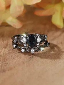 Dettaglio macro di anelli neri vintage con pietra di sabbia blu a pera e zirconi bianchi