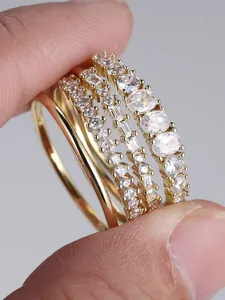 Macro detail of four gold-plated rings with oval and rectangular cubic zirconia stones