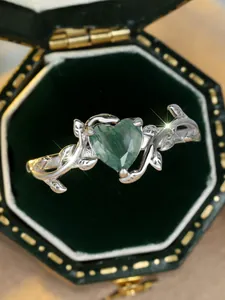 Macro shot of silver vine and leaf band with heart-cut green moss agate in a velvet box