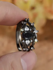 Dettaglio ravvicinato di un set di anelli con pietra di sabbia blu, placcatura in oro nero e zirconi