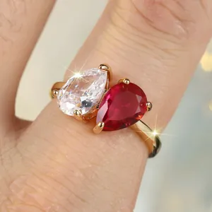 Bague dorée avec deux zircons poire rouge et clair sur le doigt d'une femme