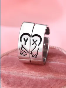 Dettaglio di anelli per coppia in argento con cuore e lettere Y X incise sulla fascia
