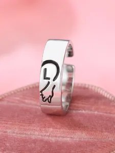 Dettaglio macro di anello d'argento con contorno a cuore, lettera L e motivo zampa di gatto
