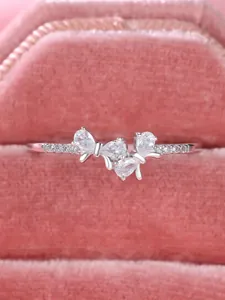 Macro shot of silver bow ring with sparkling zircons in a pink velvet jewelry box