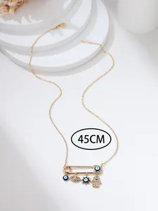 Detail of 45cm gold safety pin necklace with Hamsa hand and evil eye charms