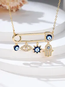 Detailed macro view of golden paperclip pendant with evil eye and hamsa hand charms