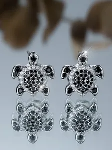 Makroaufnahme der silbernen Schildkröten-Ohrstecker mit schwarz-weißen Diamantdetails