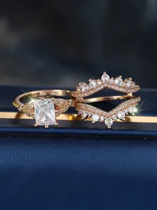 Vista macro de set de anillos en oro rosa con circón rectangular y banda en forma de V
