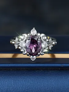 Detailed close-up of oval purple gemstone ring with white diamonds on blue velvet