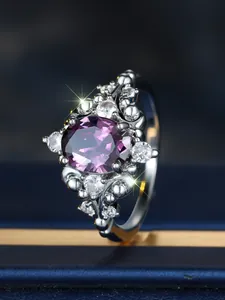 Close-up of egg-shaped purple gemstone ring with white crystals on a blue box