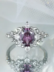 Macro view of oval purple gemstone ring with intricate silver hollow-out flower pattern